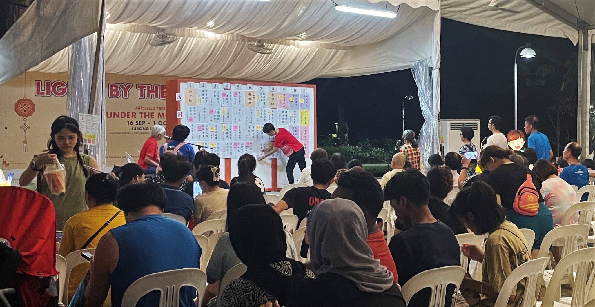 eventgoers participating in lantern riddles displayed on a board